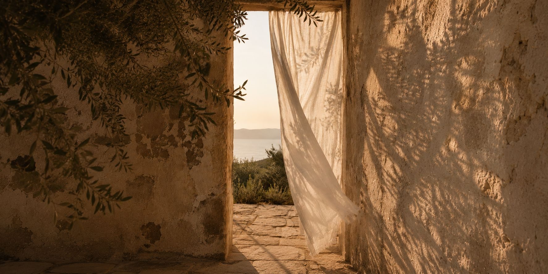 A linen curtain lifting in a stone doorway, the sea beyond