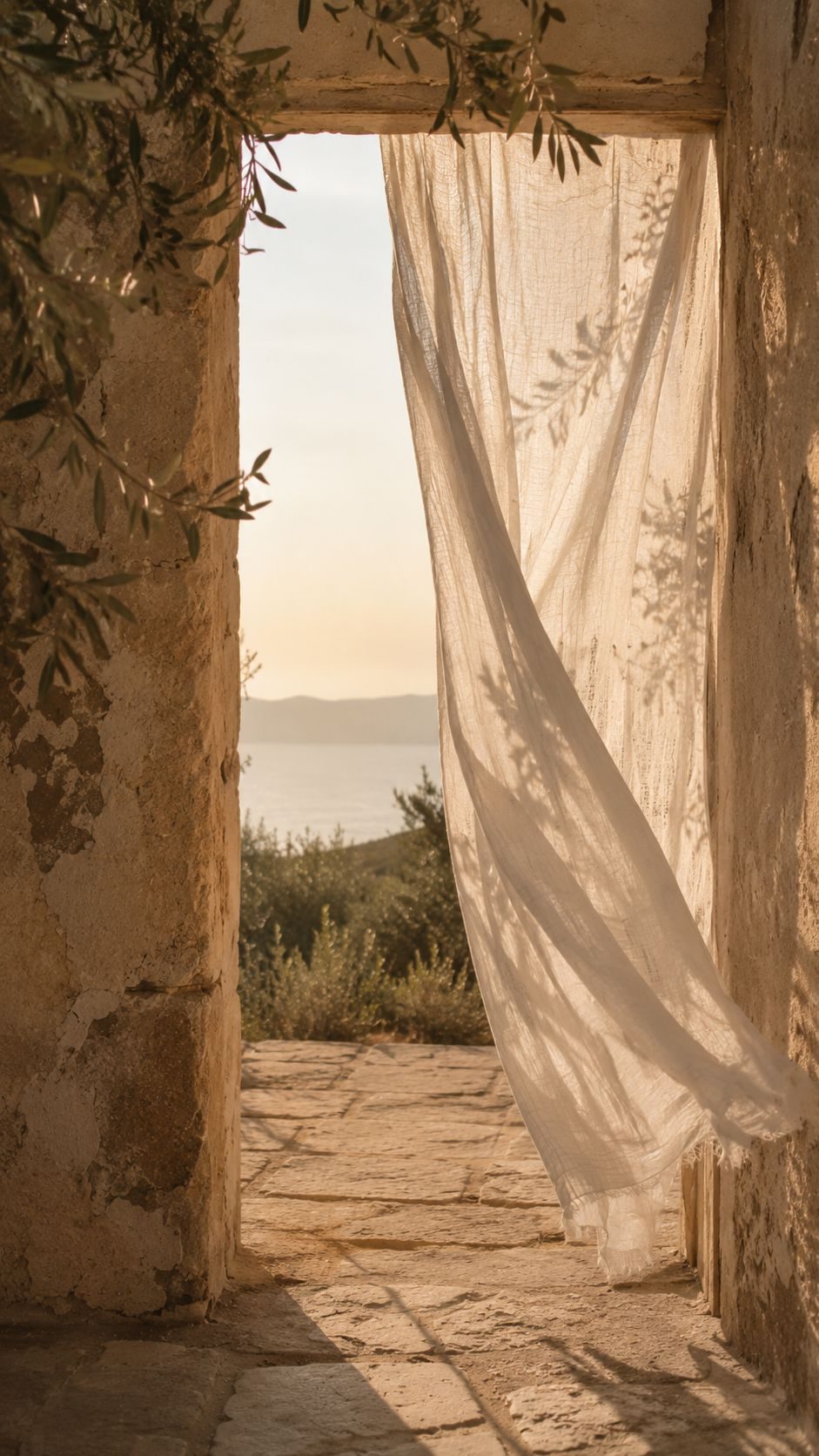 A linen curtain lifting in a stone doorway, the sea beyond